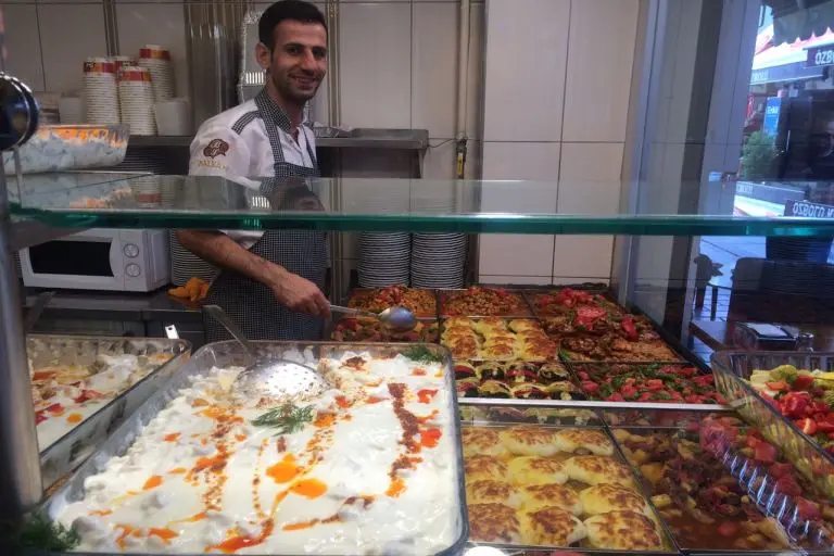 A chef stands in front of variety of food in trays in in Kusadasi walking tour