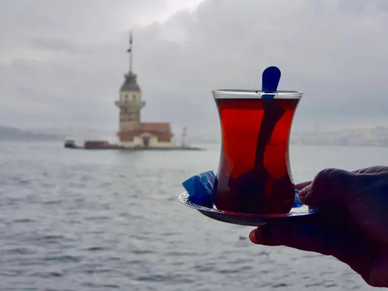A glass of traditional Turkish picture but on the background you can view the Maiden tower at Bosphorus on the Bosphorus Cruise Tour.